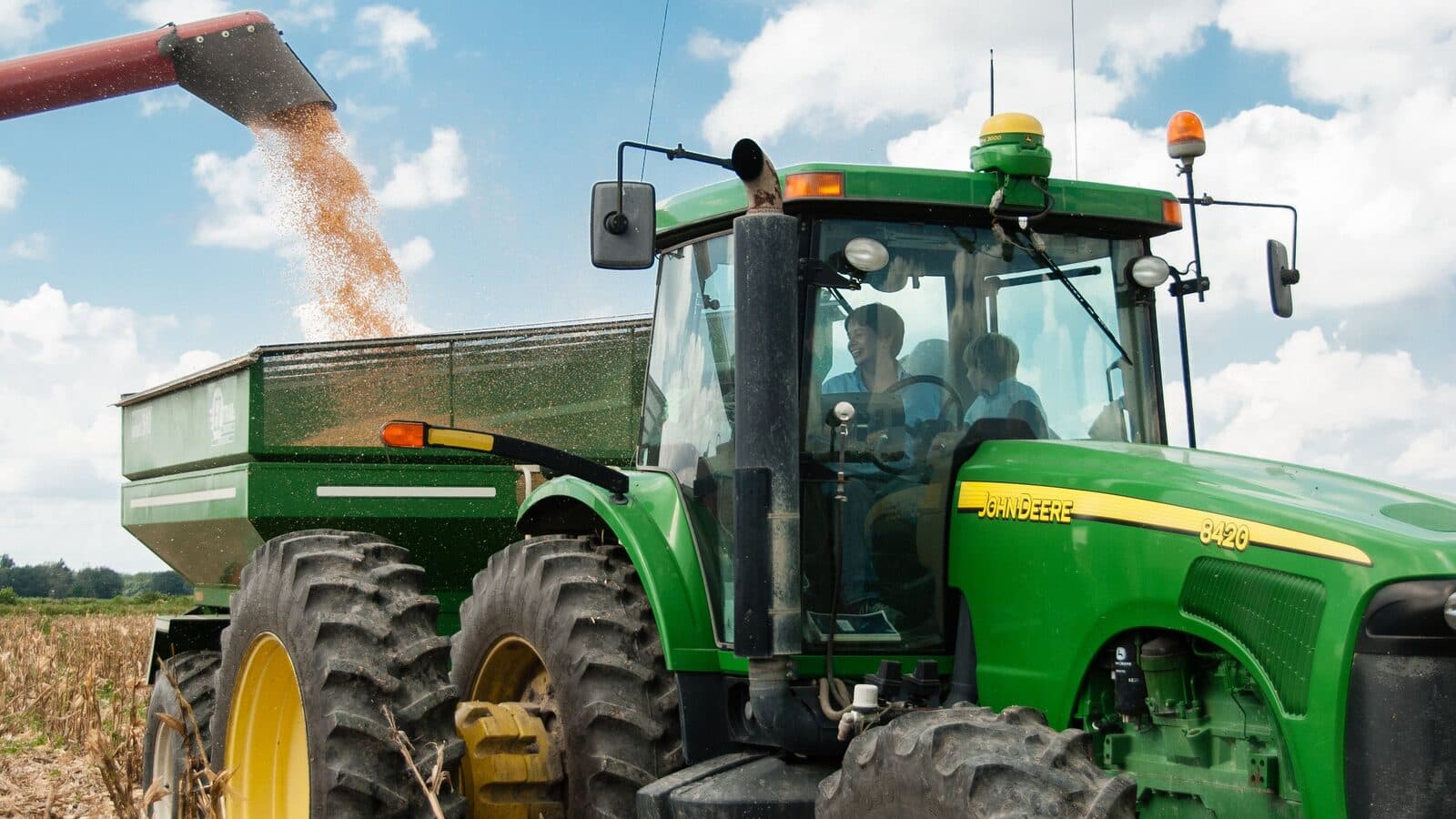 Tractor John Deere cu remorcă de cereale la recoltat
